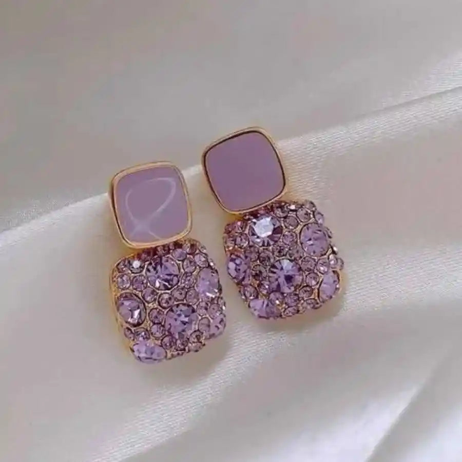 Pink earrings with gold accents on a light pink background